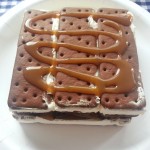 Make your own ice cream cake using ice cream sandwiches, chocolate sauce, caramel and cool whip for an easy, delicious treat | Ice Cream Sandwich Cake