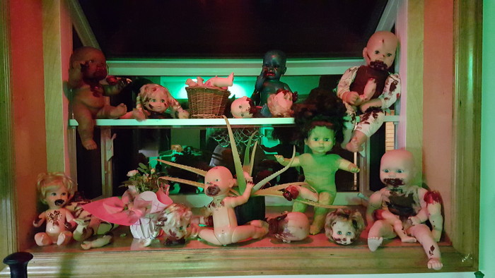 The green glow from the house and the red illumination from the light over the sink made these creepy baby dolls in kitchen window even worse