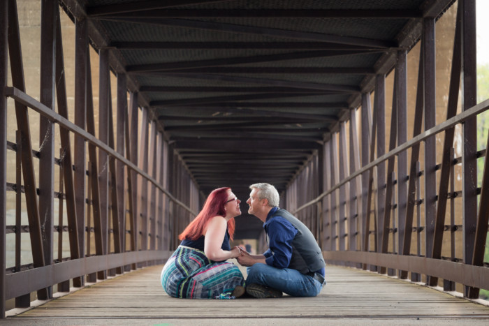 engagement photo session on a bridge, sitting indian style kissing