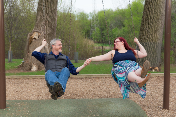 engagement photo session at a playground on the swings