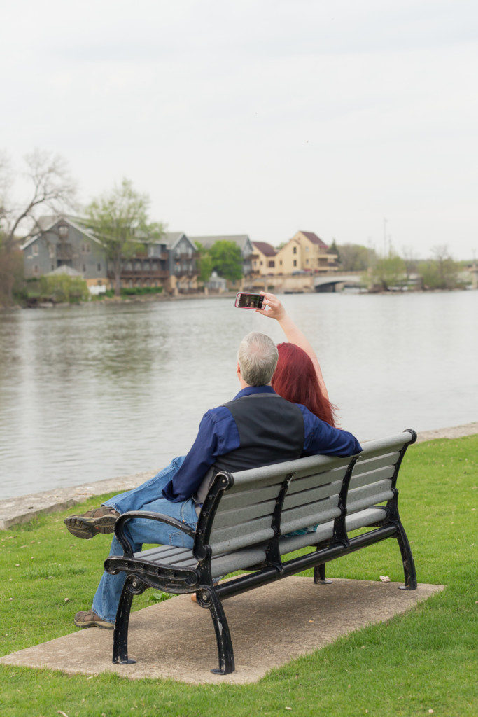 engagement photo session on a park bench taking a selfie