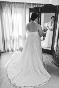 Black and white bridal photo in front of a tri-fold mirror in bride's bedroom