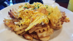 Breakfast nachos at Brunch: a plate of waffle fries, cheese, bacon, and eggs.
