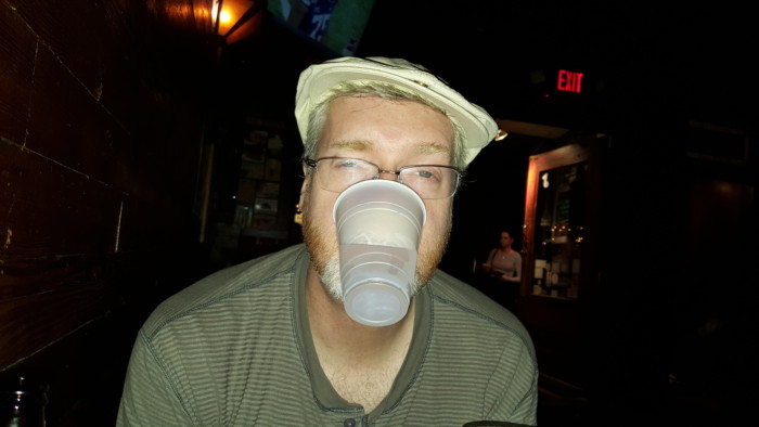 Drunk Brian holding a cup with his mouth.