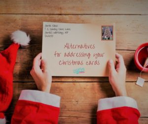 Santa holding an envelope that says alternatives for addressing your Christmas cards