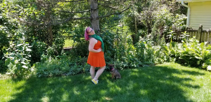 Chrissy wearing an orange dress and green scarf with yellow sneakers for an Orange Bird Disneybound.