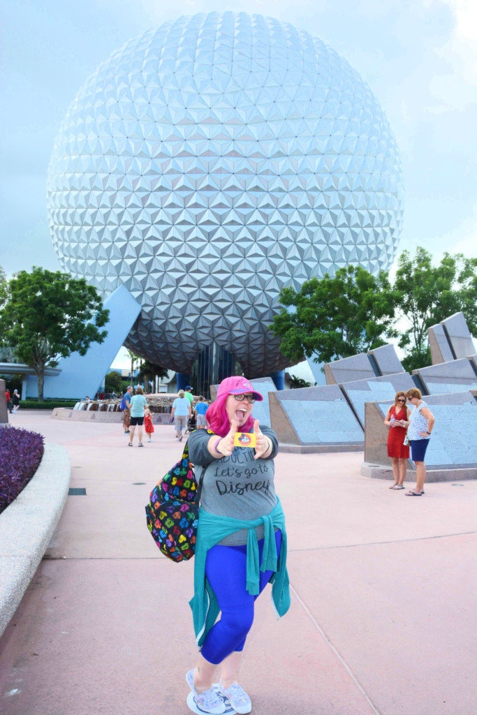 Woman Holding annual passholder card in front of EPCOT Spaceship Earth