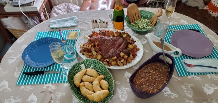 Easter dinner with lamb roast, vegetables, rolls, salad, sweet potato casserole, and champagne.