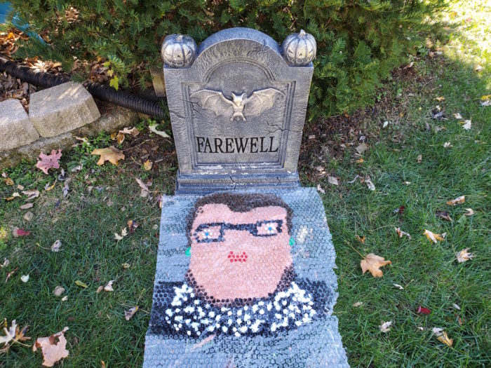 A painting of RBG in bubble wrap in front of a Halloween tombstone